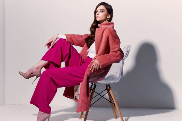 High fashion portrait of young elegant woman. Coral coat, magenta pants, white blouse. White background - Foto, afbeelding