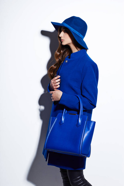 High fashion portrait of young elegant woman. Blue coat, hat, bag. White background - Φωτογραφία, εικόνα