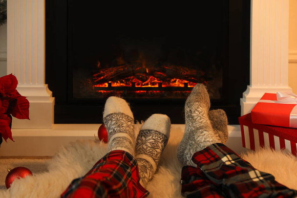 Couple in warm socks resting near fireplace at home, closeup - Photo, image