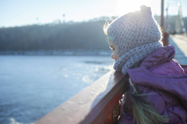 Dziecko przechodzące zimą przez most dla pieszych, zimna temperatura i słoneczny dzień - Zdjęcie, obraz