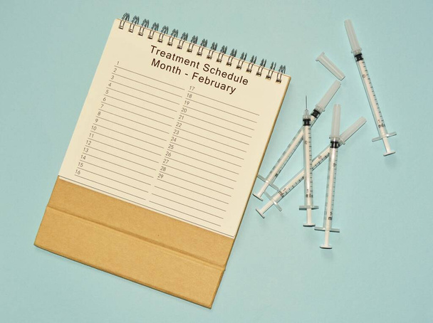 Kalendář únorového léčebného schématu a jednorázová injekční stříkačka - Fotografie, Obrázek