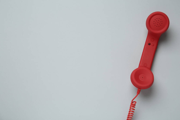 Red corded telephone handset on light grey background, top view. Hotline concept - Foto, afbeelding