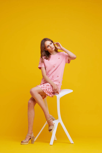Beautiful young woman in pink dress. Yellow background, fashion studio shot. - Foto, imagen