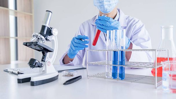 Medizinischer oder wissenschaftlicher Forscher oder Arzt, der in einem Labor ein Reagenzglas mit klarer Lösung betrachtet - Foto, Bild