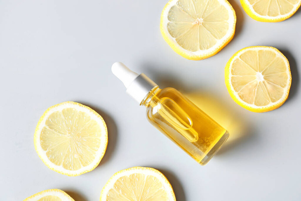 Bottle of lemon essential oil on light background - Φωτογραφία, εικόνα