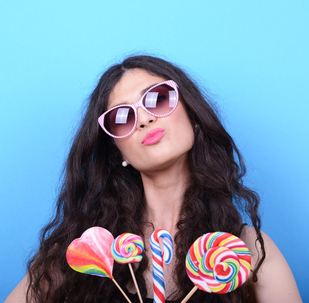 Portrait of woman with retro glasses and lollipops against blue  - Foto, Bild