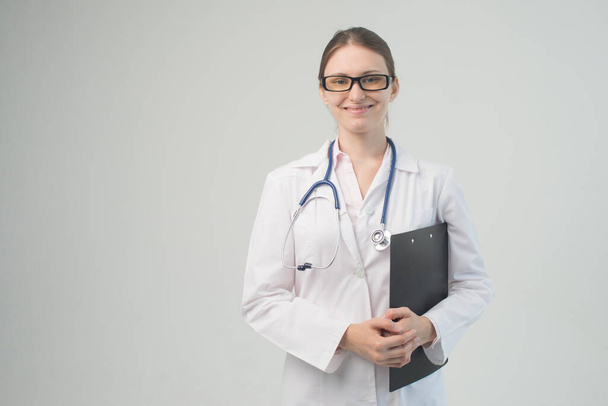 Portrait of an attractive young female doctor in white coat. - Фото, изображение