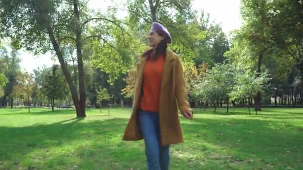 gelukkig vrouw in stijlvolle herfst outfit draait in park - Video