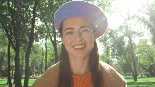 mujer alegre sonriendo a la cámara en el soleado parque de otoño - Metraje, vídeo