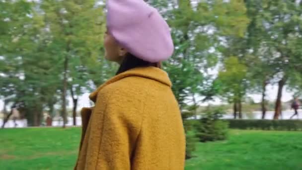 donna felice che fissa i capelli e si abbraccia in piedi nel parco - Filmati, video