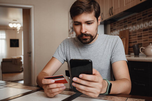 hipster joven compras en línea con tarjeta de crédito utilizando el teléfono inteligente en casa. - Foto, imagen
