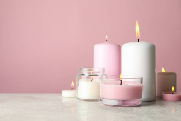 Αρωματικά κεριά για να χαλαρώσετε σε λευκό τραπέζι σε ροζ φόντο - Φωτογραφία, εικόνα