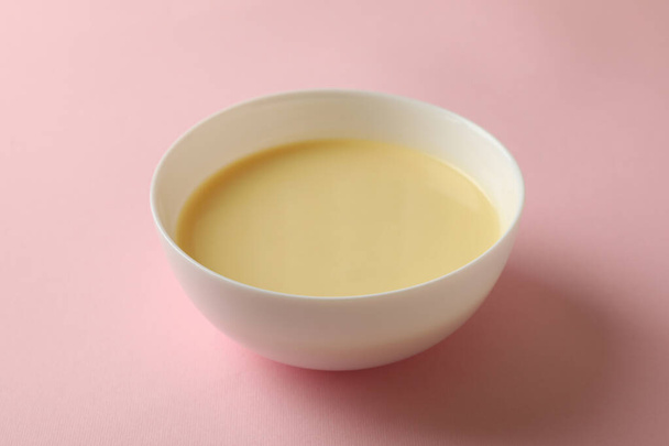 Cuenco con leche condensada sobre fondo rosa - Foto, Imagen