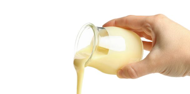Mujer vierte leche condensada de un frasco, aislado sobre fondo blanco - Foto, imagen
