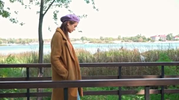 stylowa kobieta rozgląda się podczas spaceru po moście w parku - Materiał filmowy, wideo