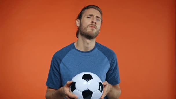 homme agressif avec ballon de football montrant aller loin geste isolé sur orange - Séquence, vidéo