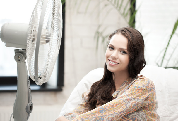 Mulher feliz e sorridente sentada perto do ventilador
 - Foto, Imagem