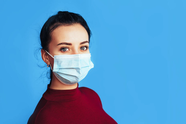 Woman in protective medical mask in front of a blue background. Health protection. Preventing disease during a pandemic. - Photo, Image