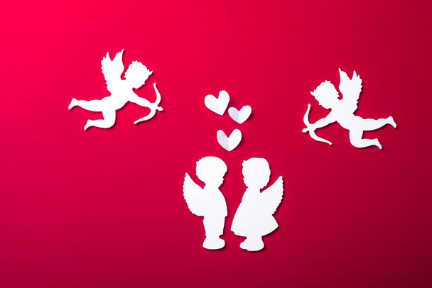 Fliegende Amor-Silhouette, zwei weiße Engel, fröhliche Valentinstag-Banner, Papierkunst-Stil. Amour auf rotem Papier - Foto, Bild