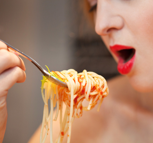 vrouw eten spaghetti in de keuken thuis - Foto, afbeelding