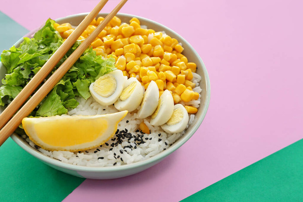 Bol avec riz savoureux, oeufs et légumes sur fond de couleur - Photo, image
