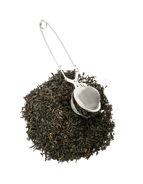 tas de feuilles de thé noir sèches avec infuseur sur fond blanc - Photo, image