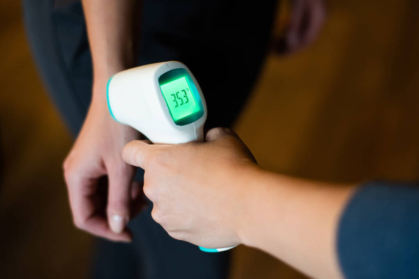 Body temperature measurement with infrared wrist thermometer. - Foto, afbeelding
