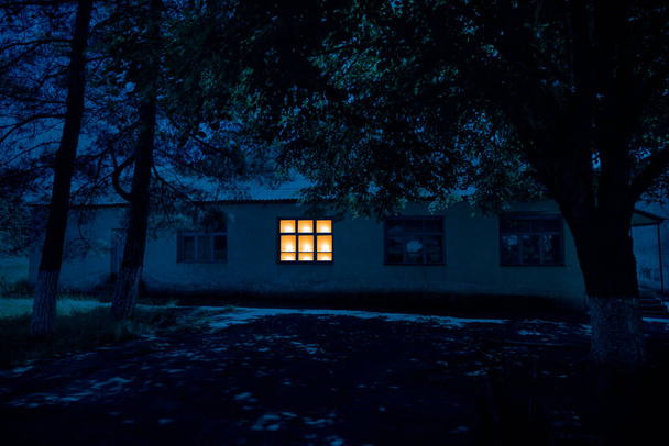 Altes Haus mit einem Geist im Wald bei nebliger Nacht oder Nachtszene mit Haus unter Mond. Altes mystisches Gebäude im toten Baumwald. - Foto, Bild