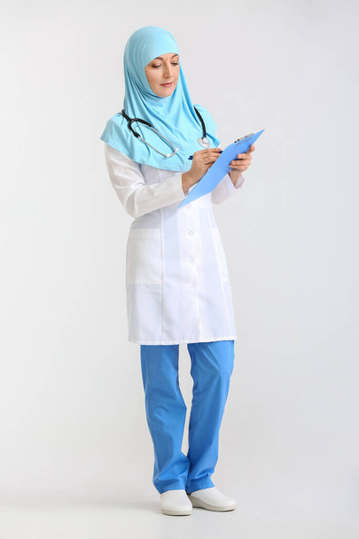 Portrait of female Muslim doctor on light background - Photo, image
