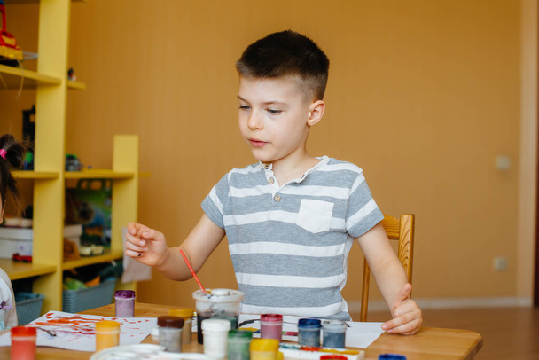 A cute little boy is playing and painting in his room. Recreation and entertainment. Stay at home - Photo, Image