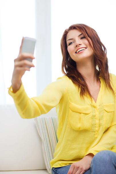 Улыбающаяся женщина со смартфоном дома
 - Фото, изображение