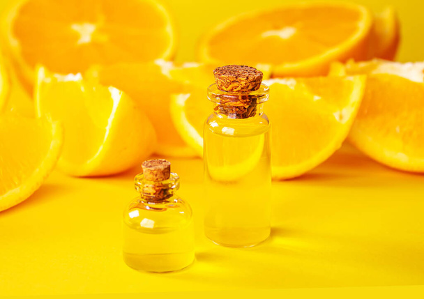 Ätherisches Orangenöl auf gelbem Hintergrund. Selektiver Fokus. - Foto, Bild