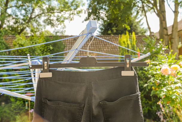 Black jeans hang drying on outdoor clothesline in spring. Close up.  - Fotografie, Obrázek