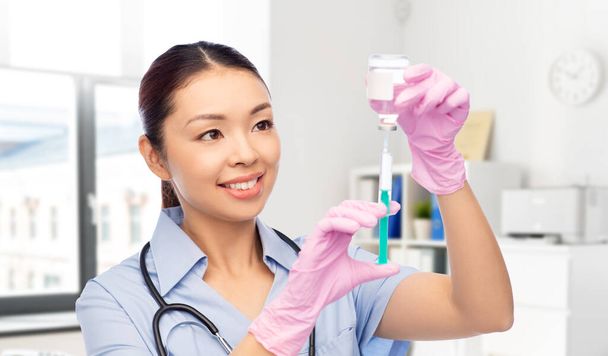 happy asian female nurse with medicine and syringe - Fotoğraf, Görsel