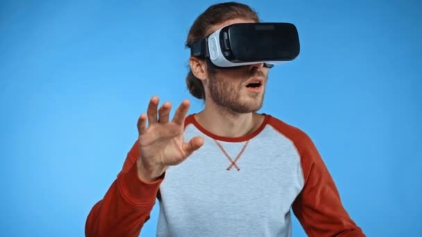 amazed man in vr headset gesturing and touching something isolated on blue - Footage, Video