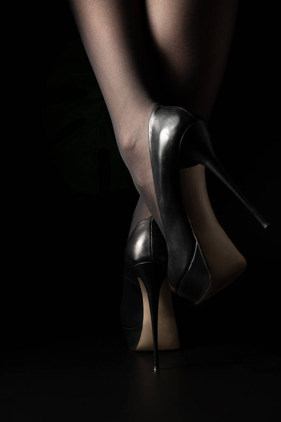 Μια γυναίκα με ψηλά τακούνια περπατάει στο σκοτάδι.. - Φωτογραφία, εικόνα