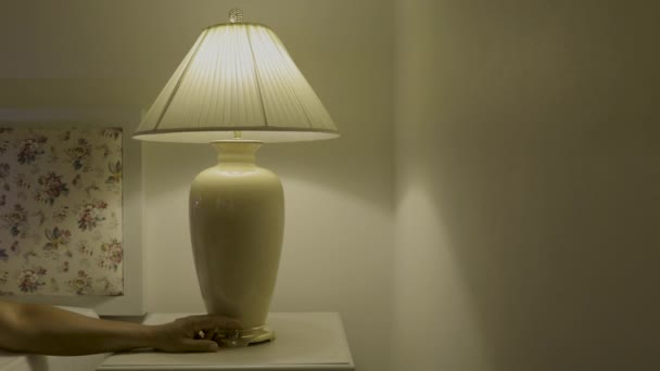 Primo piano di accensione di una lampada da tavolo in camera da letto. - Filmati, video