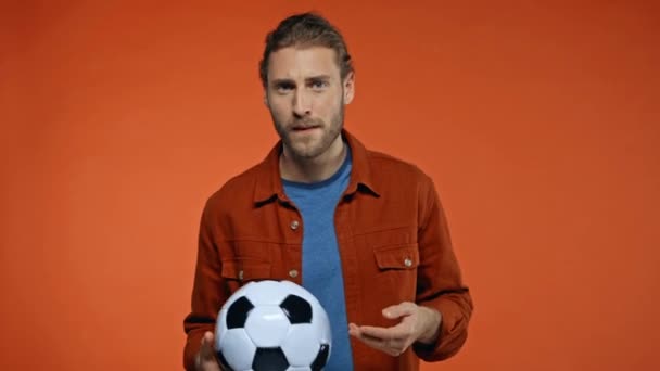 opgewonden voetbal fan kijken wedstrijd en tonen win gebaar geïsoleerd op oranje - Video