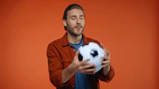 fröhlicher Fußballfan fängt Fußballball isoliert auf orange - Filmmaterial, Video