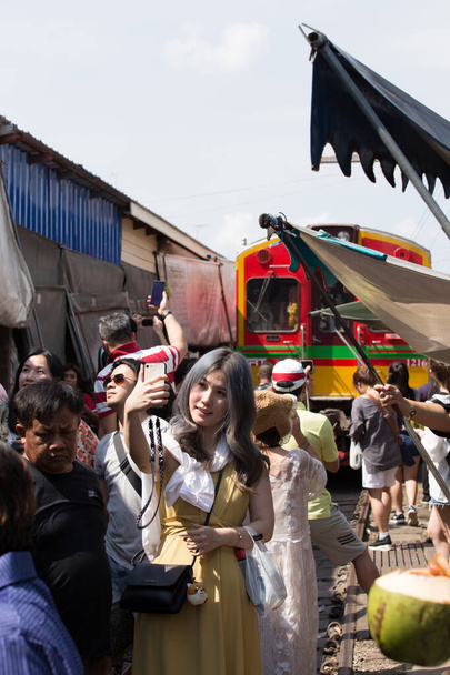 Самутсаван, Таиланд - 11 ноября 2018 года: железнодорожный рынок Maehong Railway Market, в тени вдоль железной дороги старого желтого тайского поезда на станции Mae Klong. Невидимый пункт назначения Таиланд - Фото, изображение