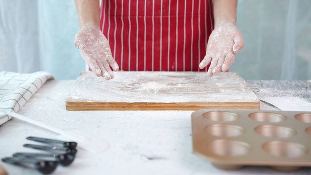 Chleb pełnoziarnisty z domowego ciasta pełnoziarnistego, wykonany przez kobietę w czerwonym fartuchu. Zdrowe ciasto z wieloma ziarnami. - Zdjęcie, obraz