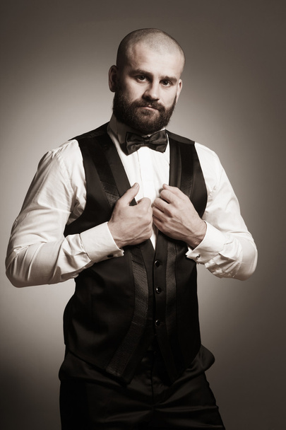 Stylish and brutal bald man with a beard in elegant black suit - 写真・画像