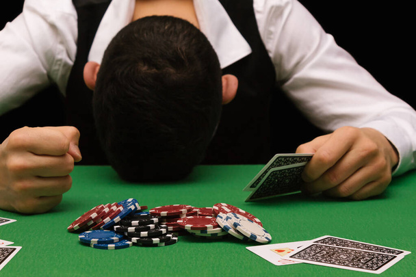 Devastated gambler man losing a lot of money playing poker in casino, gambling addiction. Divorce, loss, ruin, debt, ludopata concept. - Photo, image