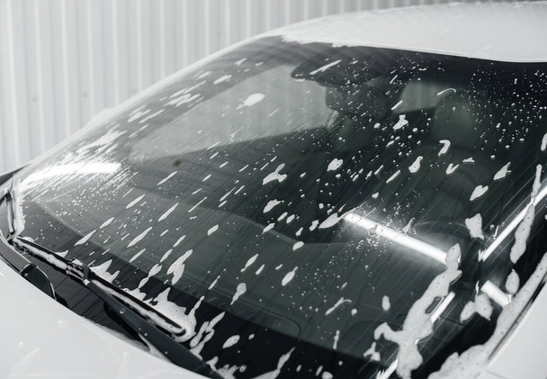 Modern washing with foam and high-pressure water of a white car. Car wash - 写真・画像