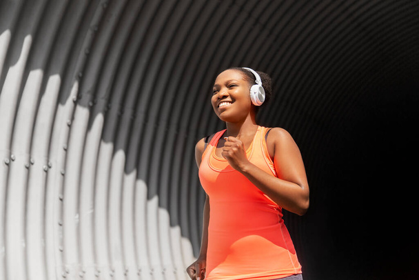 mulher africana feliz em fones de ouvido correndo ao ar livre - Foto, Imagem
