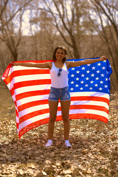 African american woman standing with american flag in hands.  Black Lives Matter - BLM idea. springtime season. last year's foliage. Smiley face. 4th july - independence day in USA. - Photo, image