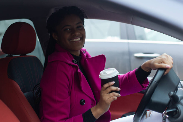 die schöne afrikanisch-amerikanische Frau im Auto mit Kaffee - Foto, Bild