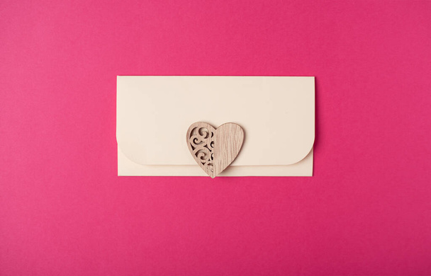Envelope and wooden heart on the hot pink background. Flat lay. Romantic love letter for Valentine's day concept. - Foto, immagini