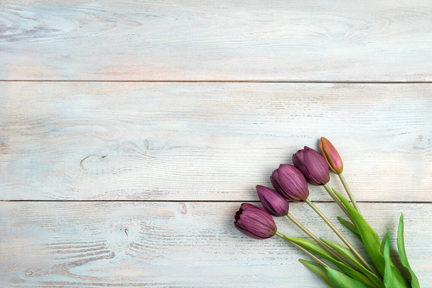 5 beautiful tulips on a light wooden background. Top view with space to copy. - Photo, Image