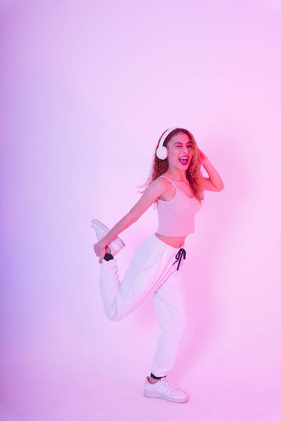 Молода азіатська дівчина в рожевій тканині слухати музику і танцювати ізольовано на неоновому світлому фоні
. - Фото, зображення